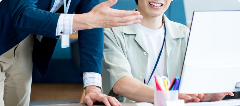 オフィスで会話しながらモニターを見るビジネスシーン