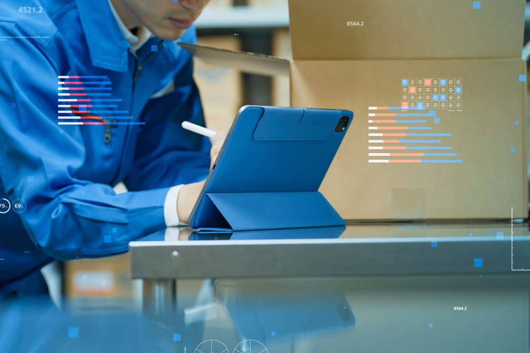 倉庫内で荷物とタブレットを確認する作業員